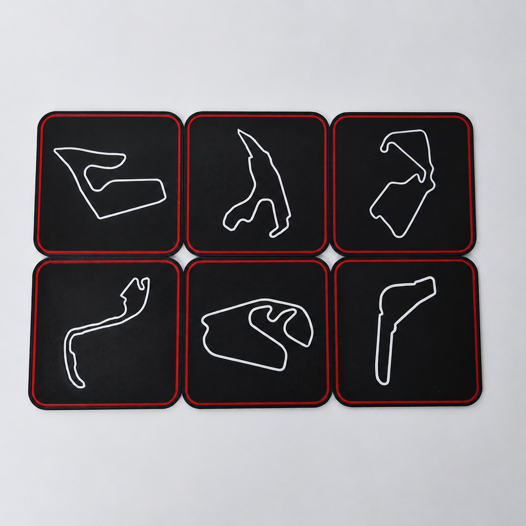 Six black square coasters with rounded corners arranged in a 2x3 grid on a light gray background. Each coaster features a white outline of a Formula 1 track circuit and has a thin red border.